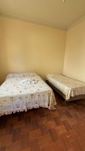 a bedroom with two beds and a wooden floor at Pousada Casa Grande in São Lourenço