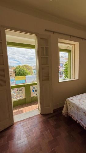a bedroom with two windows and a bed and a balcony at Pousada Casa Grande in São Lourenço