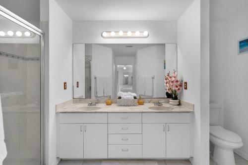 a white bathroom with two sinks and a mirror at Private Pool Home with Backyard Oasis & Family-Friendly Comfort in Cape Coral FL in Cape Coral