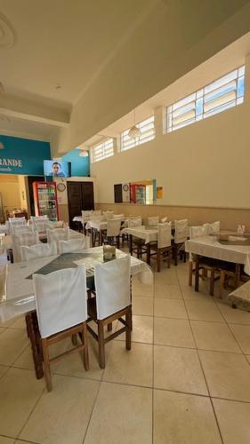 a dining room with white tables and white chairs at Pousada Casa Grande in São Lourenço