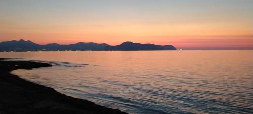 a sunset over the water with mountains in the background at Casa Mirella in Aspra