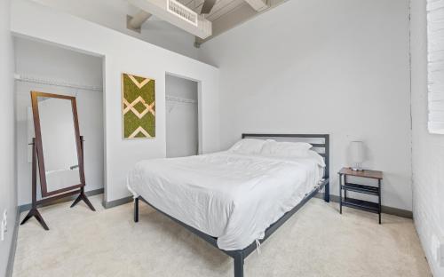 Un dormitorio blanco con una cama y un espejo. en Central 1 BD Loft l Downtown l Parking l Sofa Bed, en Cleveland