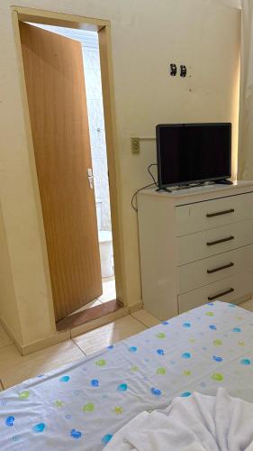 a bedroom with a bed and a dresser with a television at Pousada Casa Grande in São Lourenço