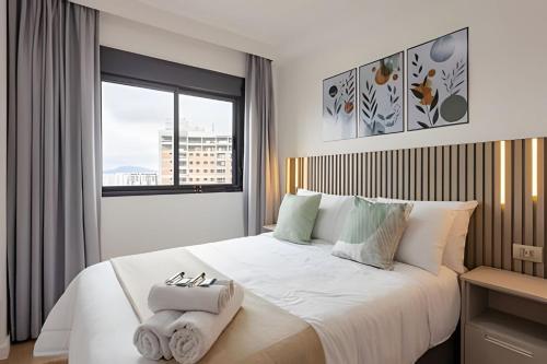 a bedroom with a large white bed with a window at Today Perdizes in Sao Paulo