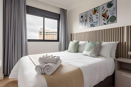 a bedroom with a large white bed with towels on it at Today Perdizes in Sao Paulo