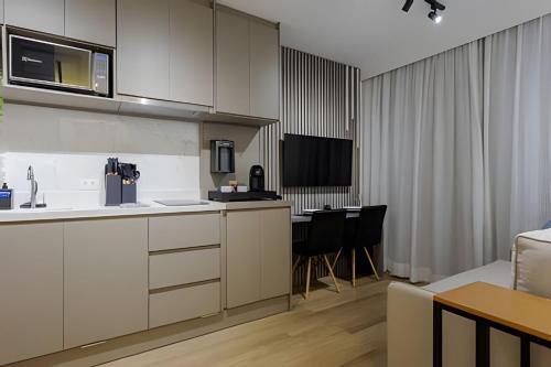 a kitchen with white cabinets and a table with chairs at Today Perdizes in Sao Paulo