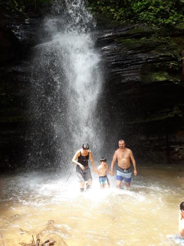 three people standing in the water in front of a waterfall at Huasquila Amazon Lodge in Cotundo