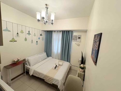 ein Schlafzimmer mit einem Bett, einem Tisch und einem Kronleuchter in der Unterkunft JJMC HOMESTAY 29 with Netflix and Wifi in Manila