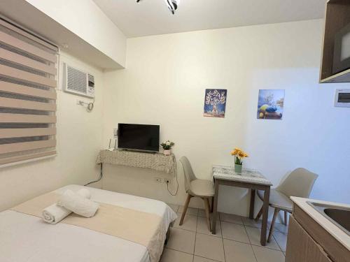 Kleines Zimmer mit einem Bett und einem Tisch mit einem TV. in der Unterkunft JJMC HOMESTAY 29 with Netflix and Wifi in Manila