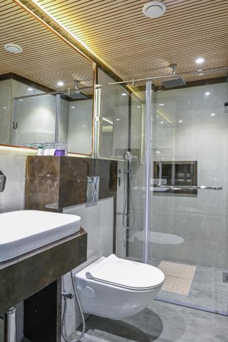 a bathroom with a toilet and a shower and a sink at Hotel Grand Girdhar Premier in Indore