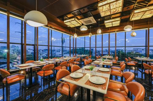 a restaurant with tables and chairs and windows at Hotel Grand Girdhar Premier in Indore