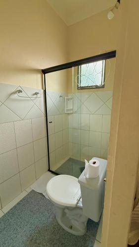 a bathroom with a toilet and a glass shower at Pousada Casa Grande in São Lourenço