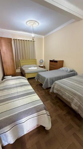 a hotel room with two beds and a chandelier at Pousada Casa Grande in São Lourenço