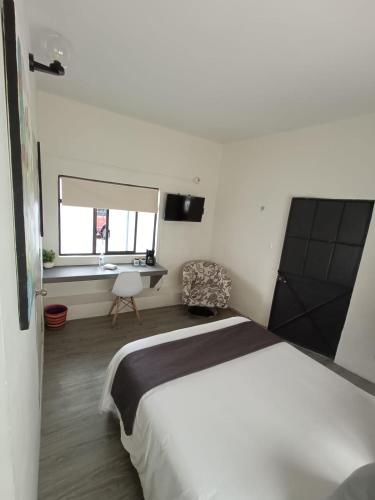 a bedroom with a bed and a desk and a window at HERMILA Tlalpan in Mexico City