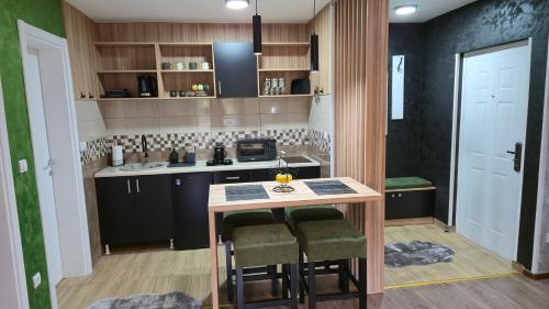 a kitchen with black cabinets and a table with stools at Apartman Tanja in Nova Varoš