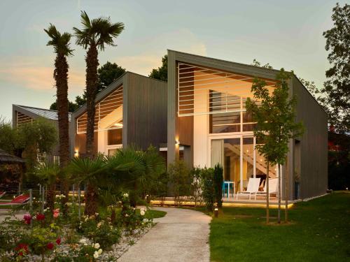 a house with a courtyard with a palm tree at Garda Sporting Club Hotel in Riva del Garda