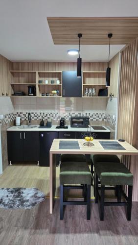 a kitchen with a table and some green chairs at Apartman Tanja in Nova Varoš