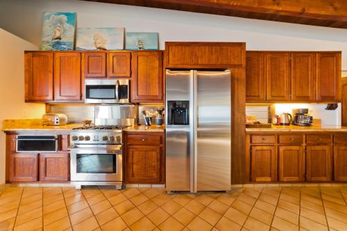 a kitchen with wooden cabinets and stainless steel appliances at Aloha Casa Miramar by SkyRun Kona Coast in Kailua-Kona
