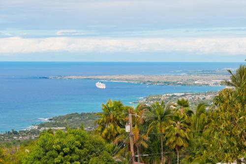 a cruise ship in the ocean with palm trees at Aloha Casa Miramar by SkyRun Kona Coast in Kailua-Kona