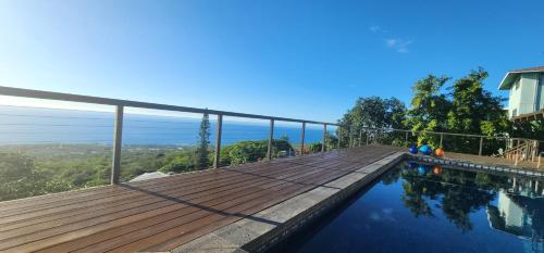 a house with a wooden deck and a swimming pool at Aloha Casa Miramar by SkyRun Kona Coast in Kailua-Kona