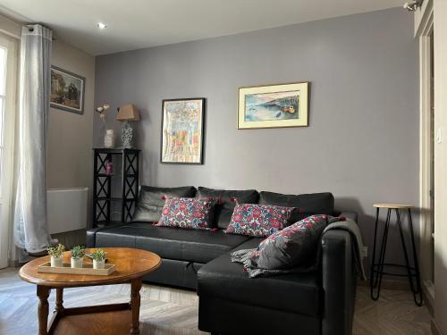 a living room with a black couch and a table at Home St. Germain in Trouville-sur-Mer