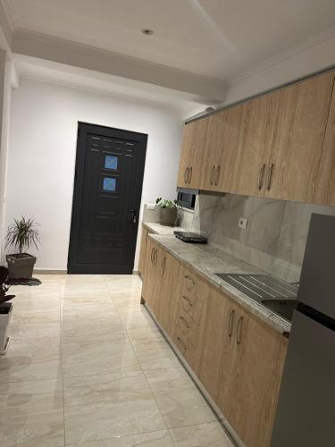 a kitchen with wooden cabinets and a black door at Villa Nava Ksamil in Polisi i Vogël