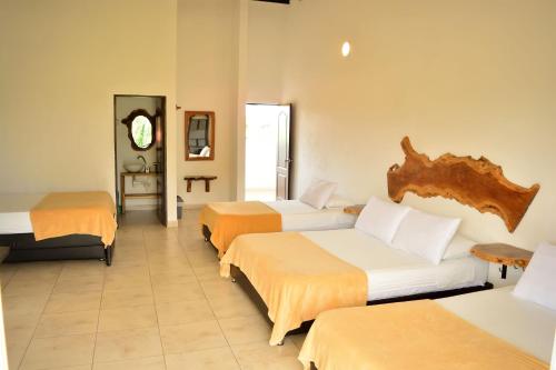 a hotel room with three beds and a clock at Finca Hotel Loma Verde in Quimbaya