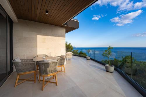 eine Terrasse mit Stühlen, einem Tisch und Meerblick in der Unterkunft Villa Mistique in Budva