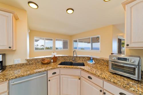 a kitchen with a sink and a stove at Kona Vistas by SkyRun Kona Coast in Kailua-Kona