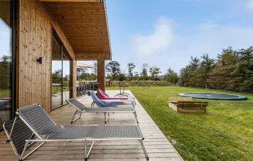 a deck with chairs and a trampoline in a yard at Amazing Home In Sæby With Sauna in Sæby
