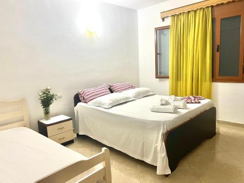 a bedroom with two beds and a yellow curtain at Dario's Apartaments 2 in Orikum