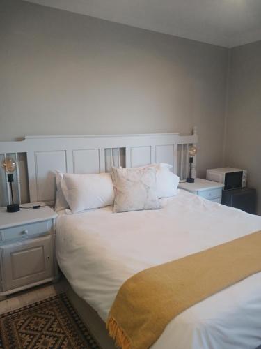 a bedroom with a large white bed with white pillows at Cozy Kosmos in Hartbeespoort