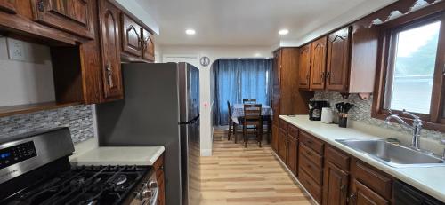 una cucina con mobili in legno e un frigorifero in acciaio inossidabile di Kenmore Avenue Niagara Buffalo New York 3-Bedroom entire home a Kenmore