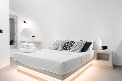 a white bedroom with a white bed with black and white pillows at AetherOia Suites in Oia