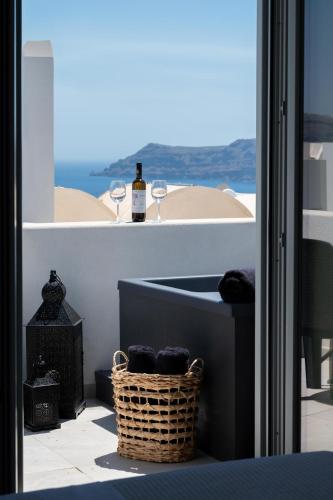 a balcony with a bottle of wine and a basket at AetherOia Suites in Oia