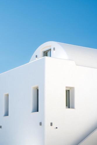 a white building with windows against a blue sky at AetherOia Suites in Oia