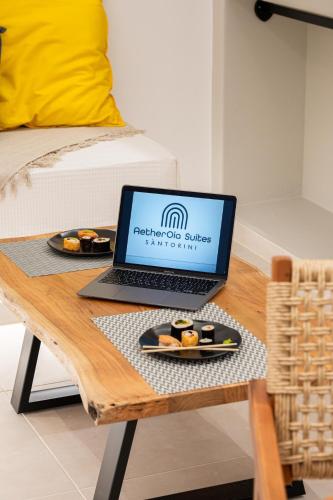 a laptop computer sitting on a table with a plate of food at AetherOia Suites in Oia