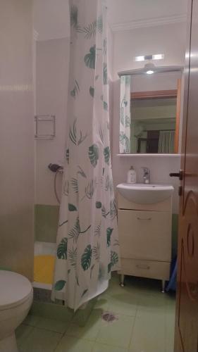a bathroom with a shower curtain with a toilet and a sink at Leon Studio Komi in Kalamoti