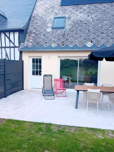 a patio with chairs and a table in front of a house at Le gîte de notre histoire in Épégard
