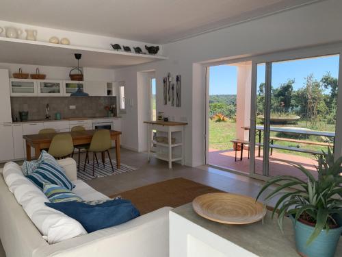 a living room with a white couch and a kitchen at Casa no Rio - River House in Vila Nova de Milfontes