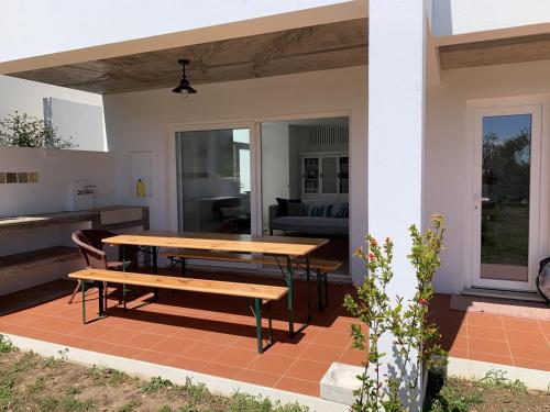 a table and a bench on a patio at Casa no Rio - River House in Vila Nova de Milfontes