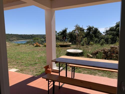 a porch with a bench and a view of a field at Casa no Rio - River House in Vila Nova de Milfontes