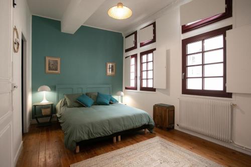 1 dormitorio con paredes azules y 1 cama con almohadas azules en La Luciole, en Périgueux