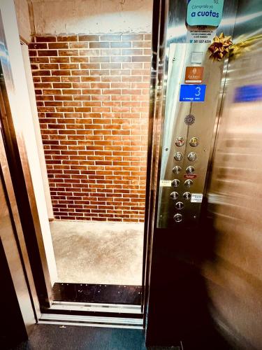 an elevator door with a brick wall and a control panel at Beautiful loft with elevator for nomad envigado in Envigado