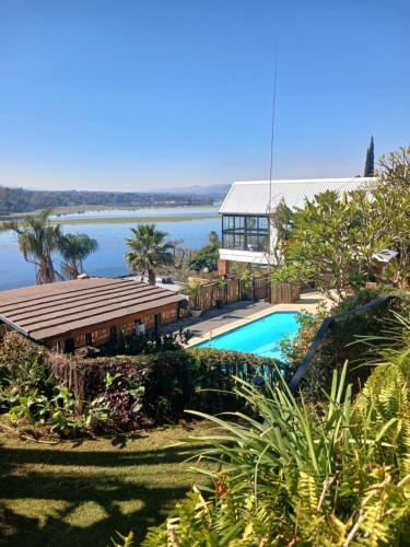 a house with a swimming pool next to a lake at Cozy Kosmos in Hartbeespoort
