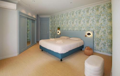 a bedroom with a bed with a blue headboard and floral wallpaper at Villa Des Artistes in Suze-la-Rousse