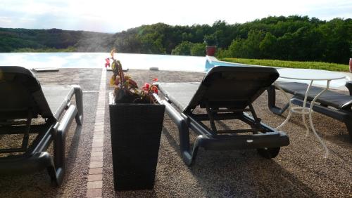 two chairs and a table on a roof with a pool at Domaine de Janis & Spa in Le Vigan