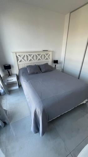 a large bed in a white room with two lamps at luxury Brickell Towers in Tigre