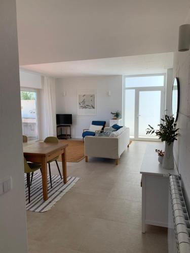 a living room with a white couch and a table at Casa no Rio - River House in Vila Nova de Milfontes