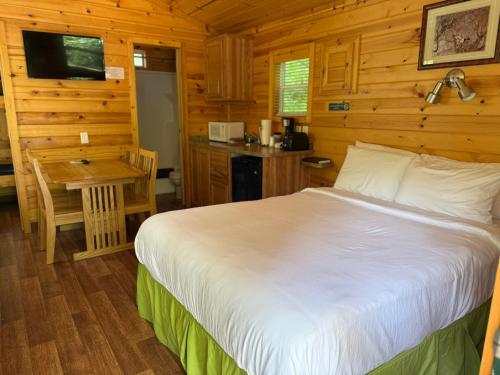 a bedroom with a bed and a table and a kitchen at Quechee Pine Valley Campground in Hartford